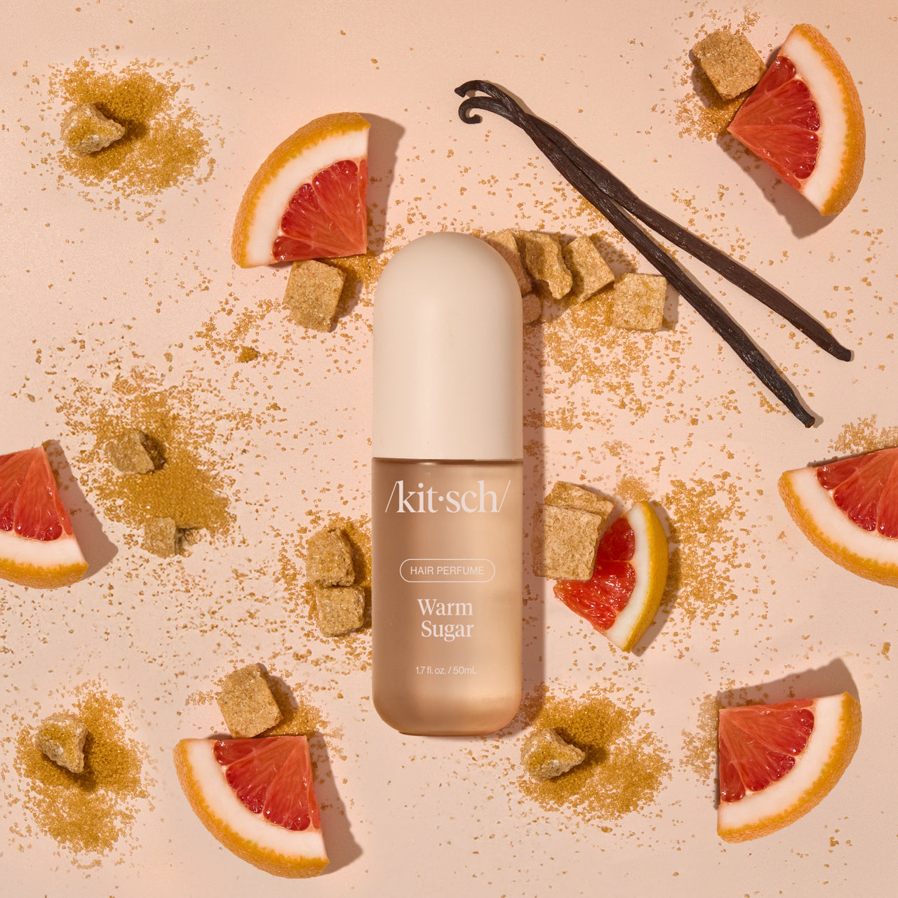 Model misting Kitsch Warm Sugar Hair Perfume onto long, smooth hair